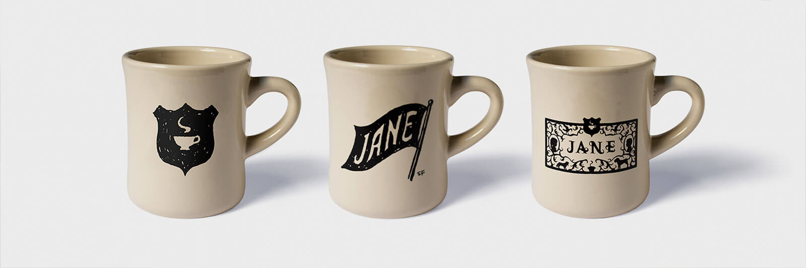 3 light tan mugs with black logos