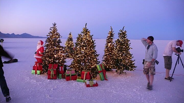 Photography crew with Christmas trees decorated with lights, gifts, and Santa statue