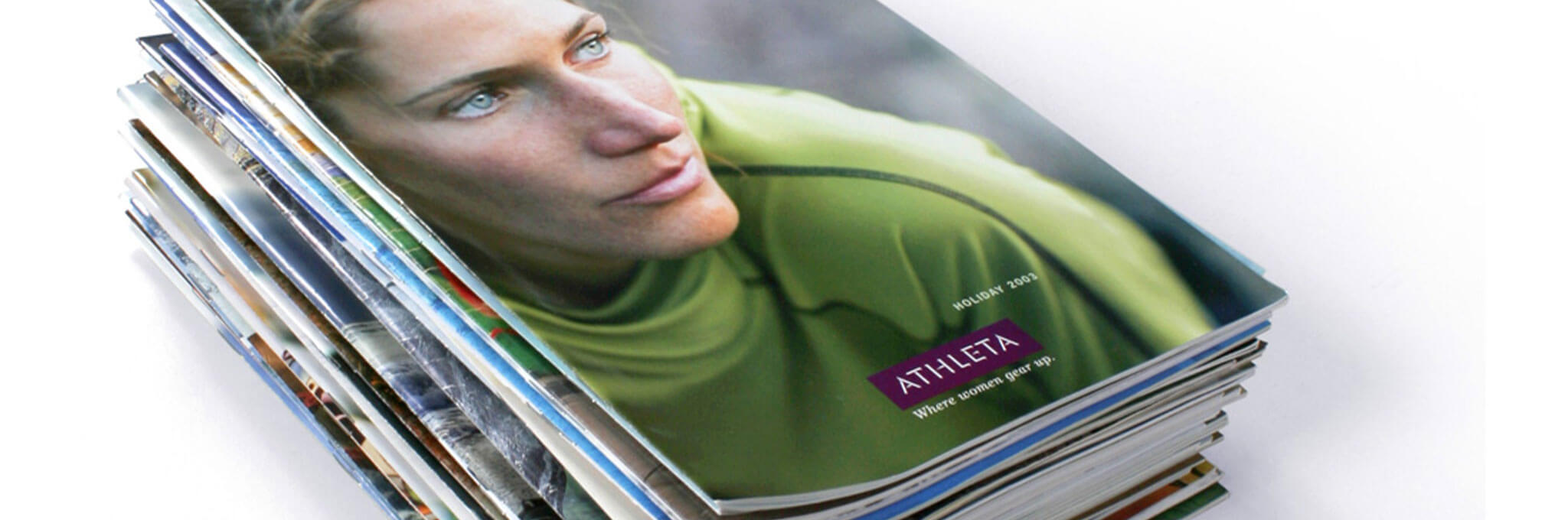 Stack of Athleta catalogs topped with cover of a woman in a green shirt
