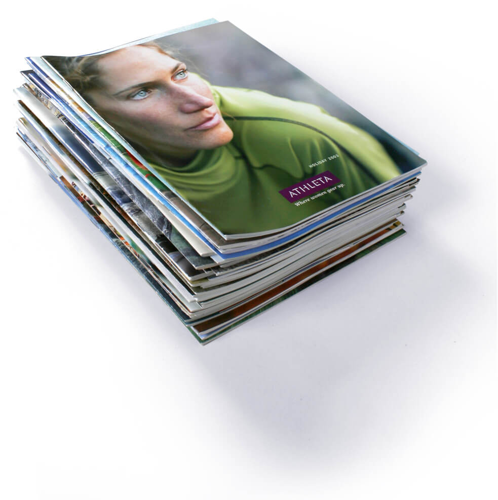 Stack of Athleta catalogs topped with cover of a woman in a green shirt