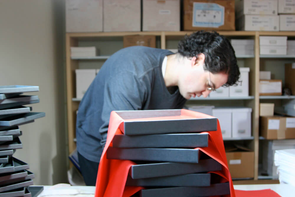 Nate behind stack of gray boxes with red tissue paper