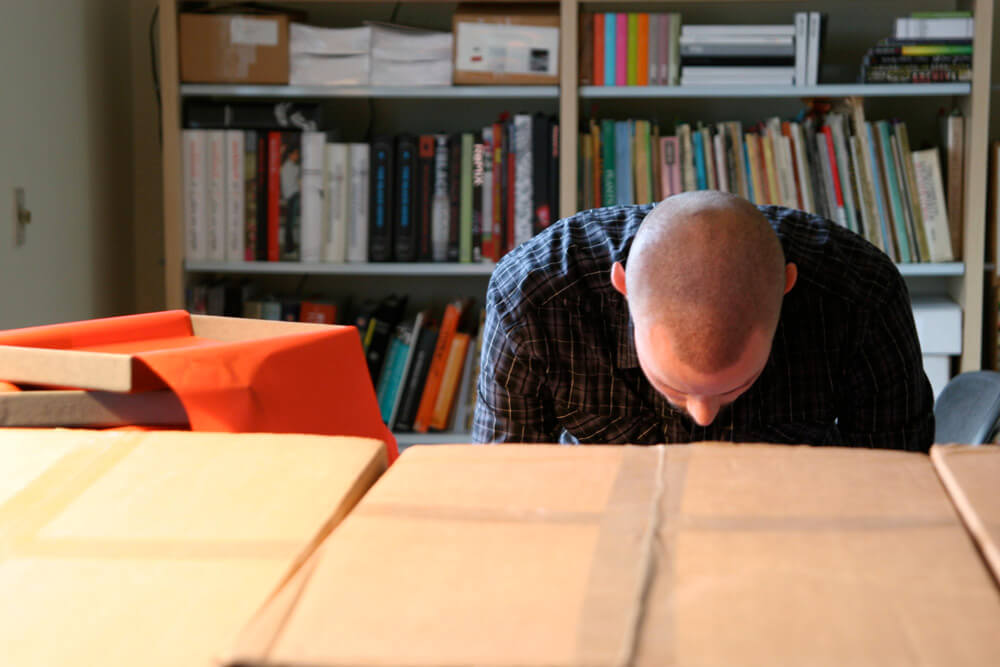 Scott leaning over behind cardboard boxes