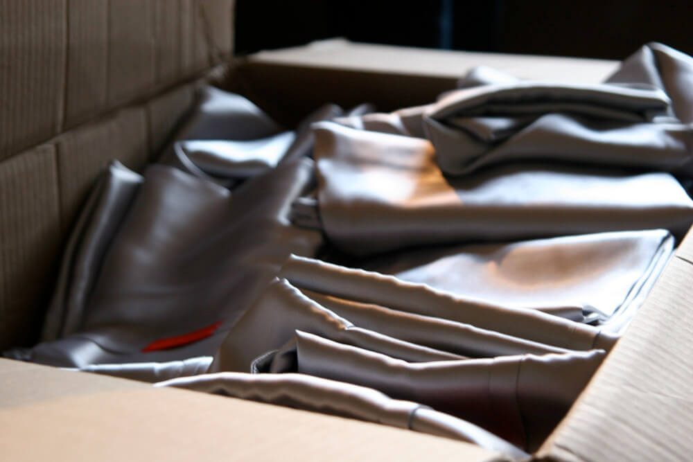 Folded silver pillow cases stacked in cardboard box