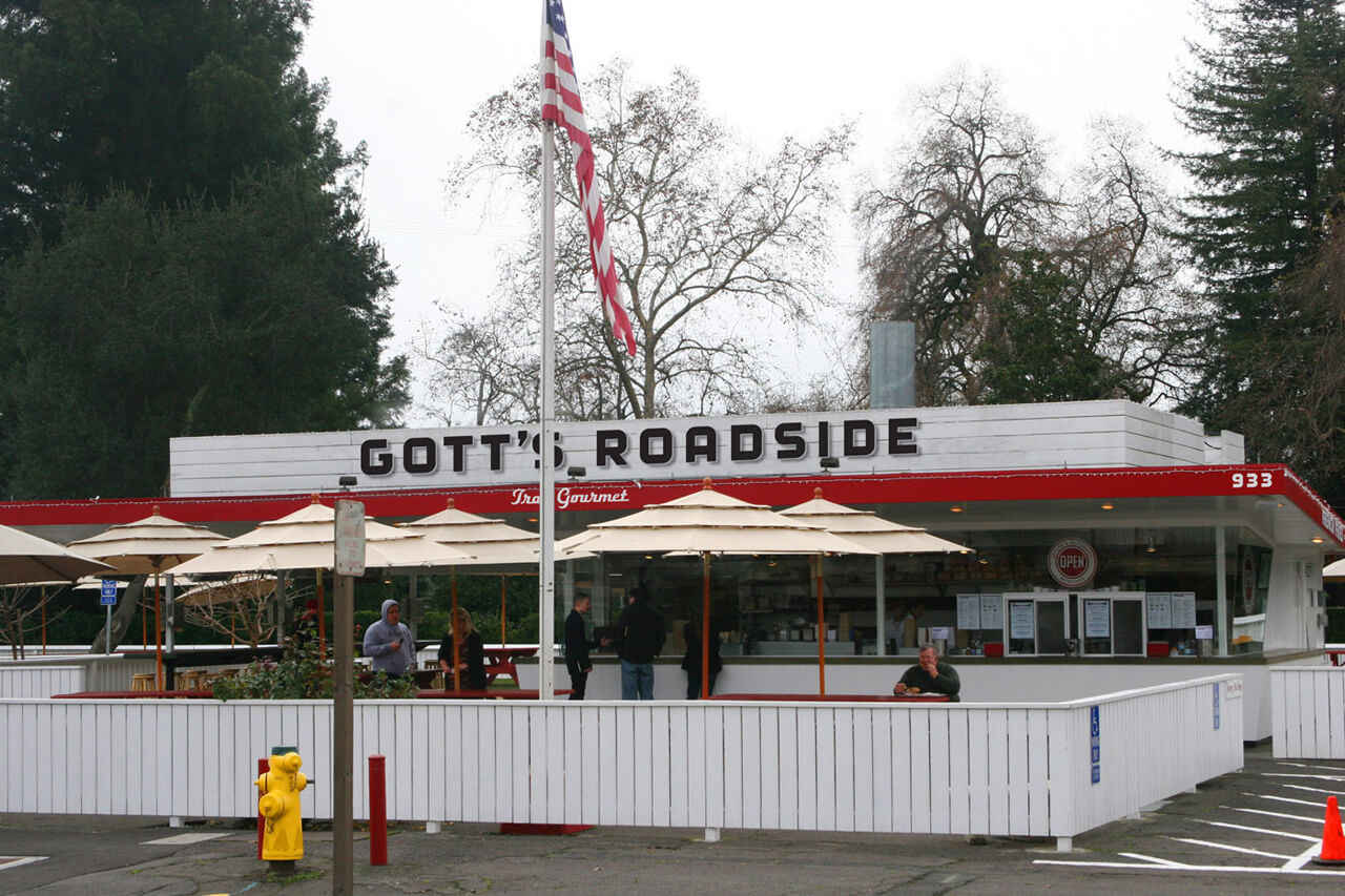 White fence around outdoor umbrella tables in front of Gott's Roadside restaurant
