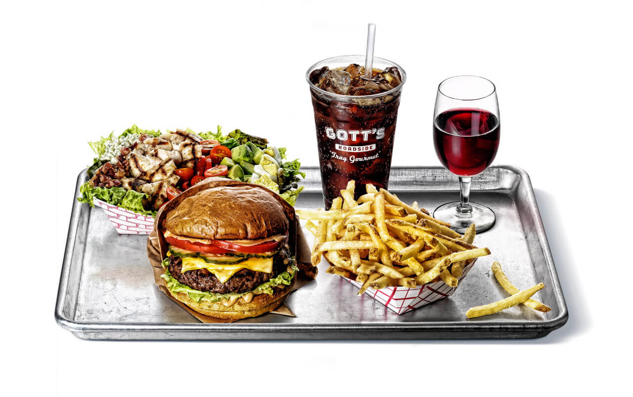 Silver tray with chicken salad, cheeseburger, soda, wine, and fries