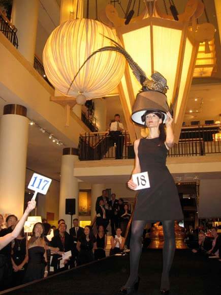 Woman wearing feathered lampshade headdress holding the #18