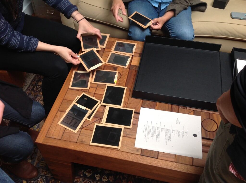 People looking at dark transparency slides at wooden table