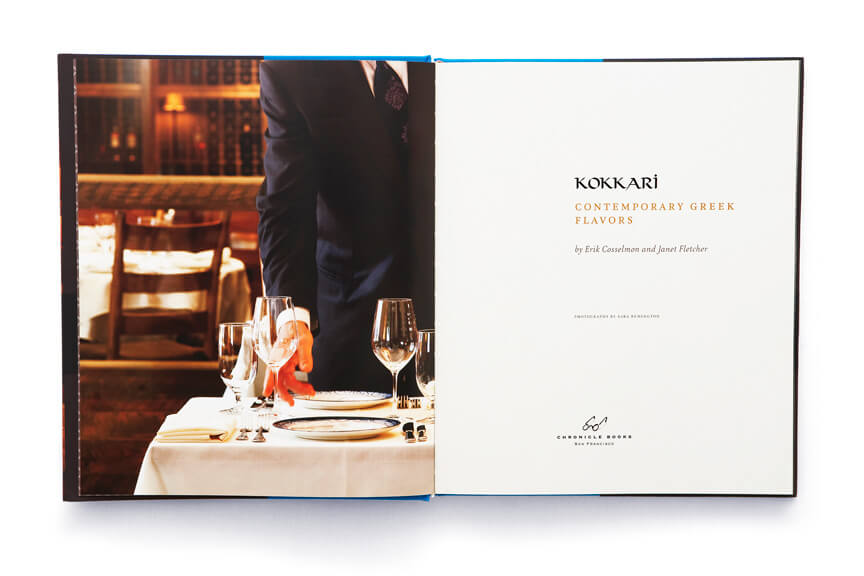 Open book showing suited man setting up glasses at dinner table adjacent to Kokkari title page