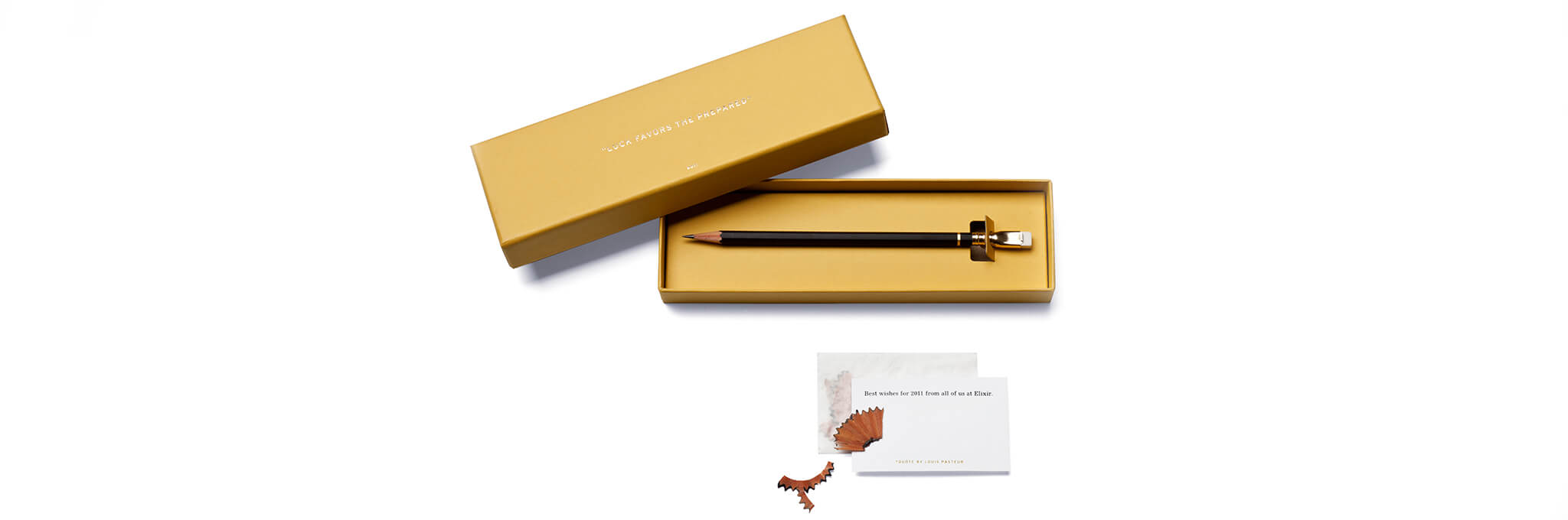 Yellow box containing one black pencil sitting above card with pencil shavings