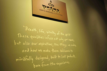 Hand-written type under prAna signage on green wall