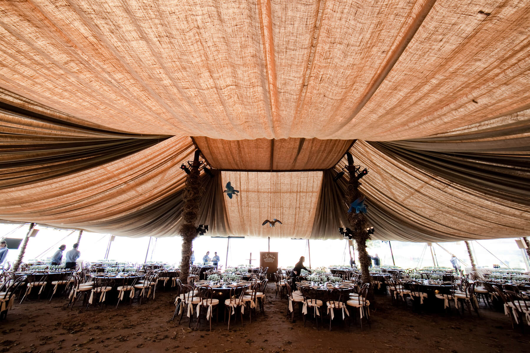 Peach and tan cloth draped ceiling above dinner tables