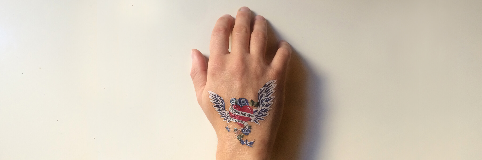 Back of right hand with winged-heart tattoo