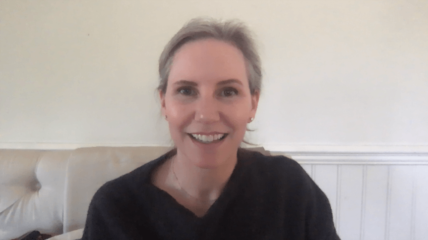 Screen shot of Meagan smiling on white sofa